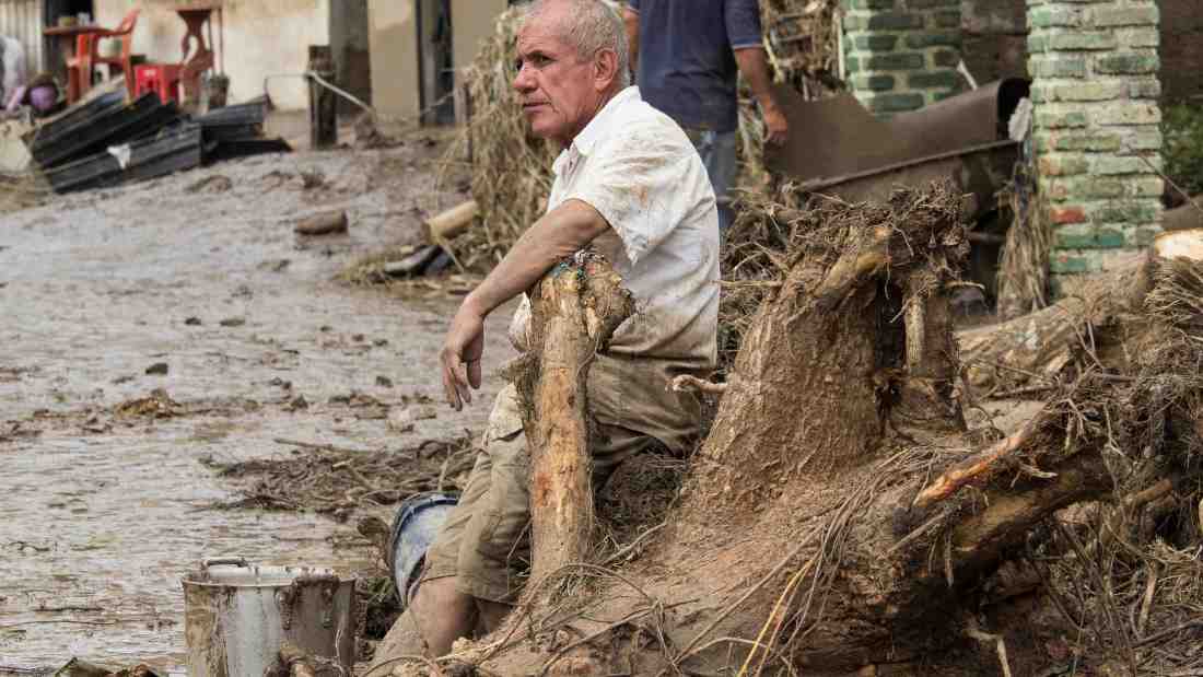 An old man sitting in the debris caused by flooding