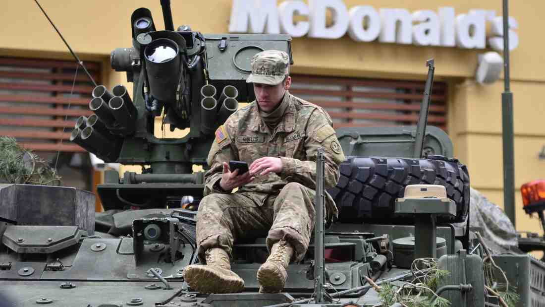 Soldier sitting on an armoured tank outside a McDonalds