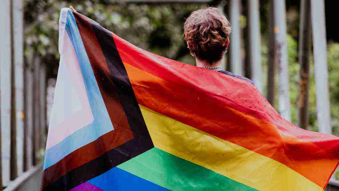 A woman holding a rainbow flag, symbolizing LGBT rights